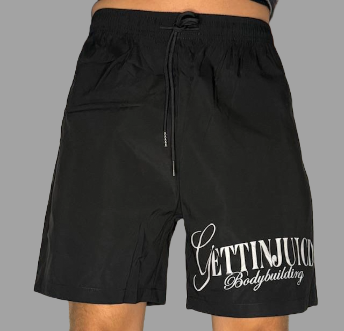 Model wearing GettinJuicd athletic gym shorts — mid-waist workout shorts for men with logo print and adjustable drawstring.